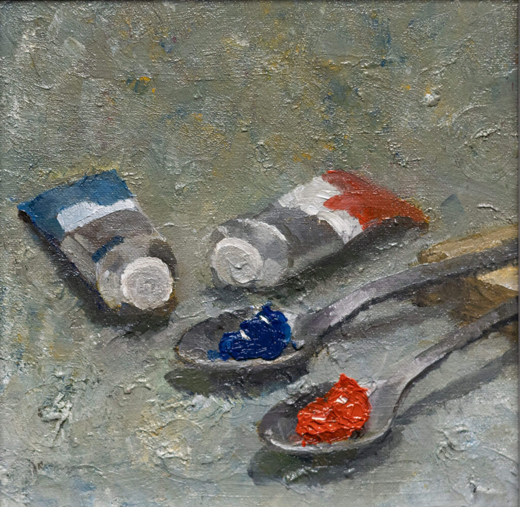 Classical still life oil painting of two silver spoons, one holding red pigment and one holding blue pigment, on a gray background.
