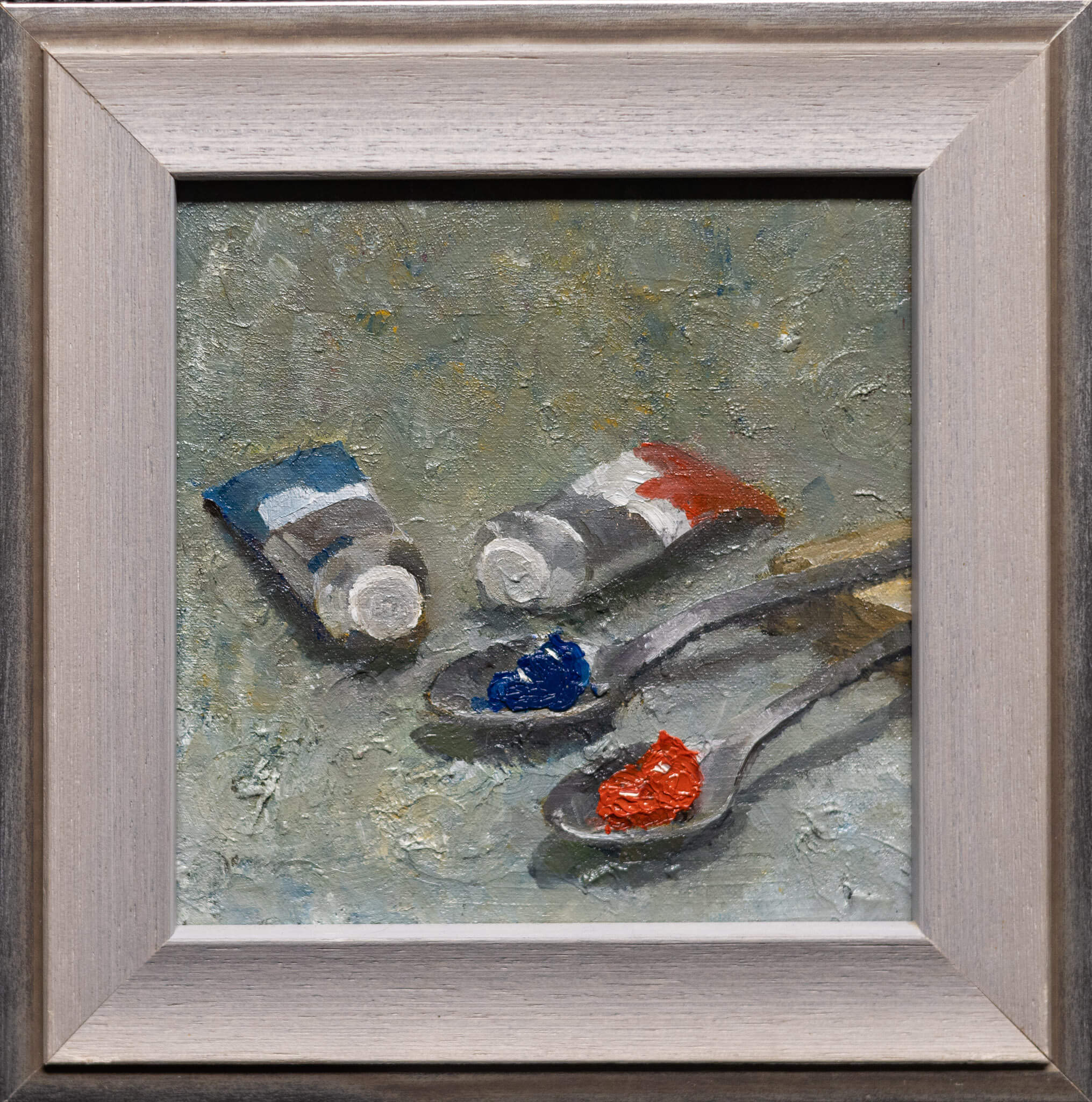 Classical still life oil painting of two silver spoons, one holding red pigment and one holding blue pigment, on a dark background.