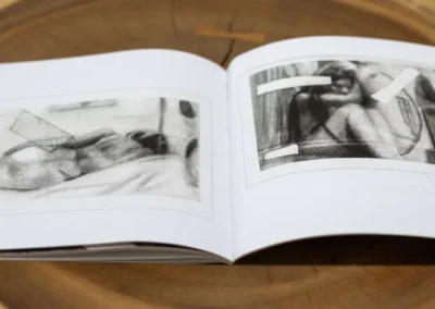 Inner Body open spread showing a reclining figure and a crouched figure in soft charcoal